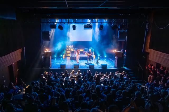 La scène et le public d’un concert de Charlie Oz sous les lumières bleues